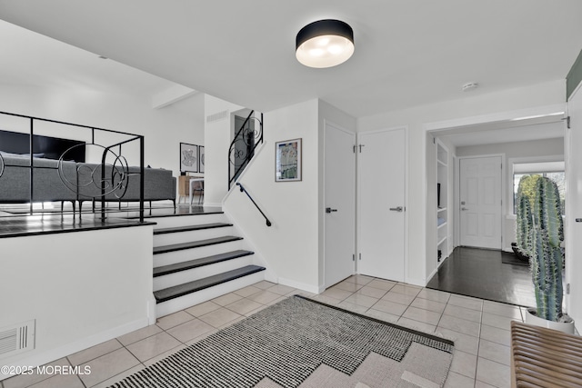 entrance foyer with visible vents, stairway, baseboards, and light tile patterned floors