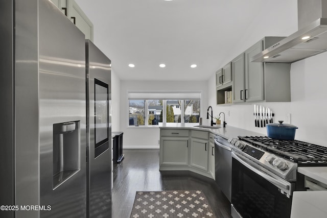 kitchen with a sink, light countertops, appliances with stainless steel finishes, wall chimney range hood, and gray cabinets