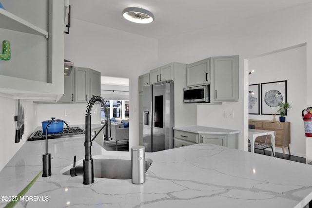 kitchen with gray cabinets, light stone counters, and stainless steel appliances