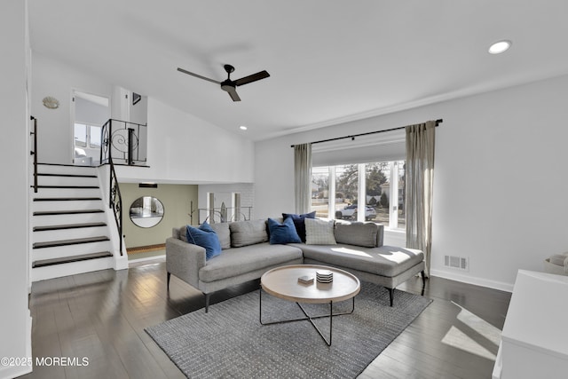 living area with visible vents, a ceiling fan, stairway, dark wood-style flooring, and vaulted ceiling