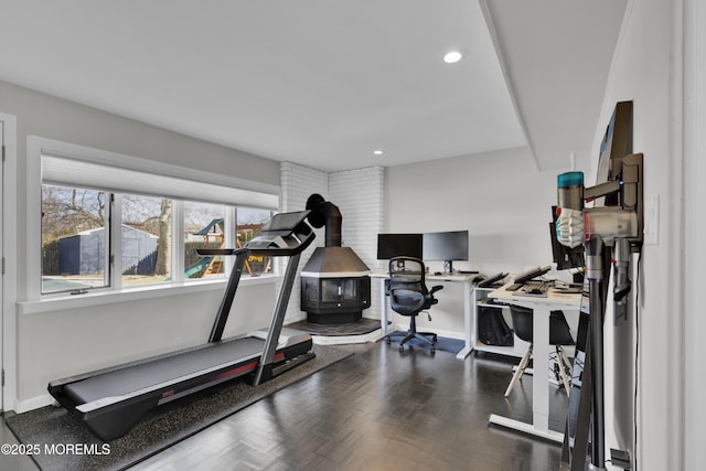 exercise room with a wood stove, dark wood-style floors, baseboards, and recessed lighting