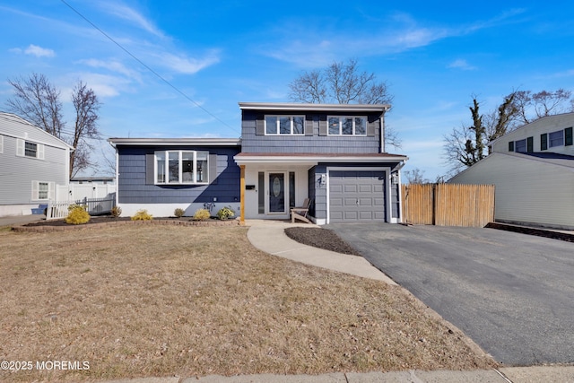 view of front of home with driveway, a front lawn, an attached garage, and fence