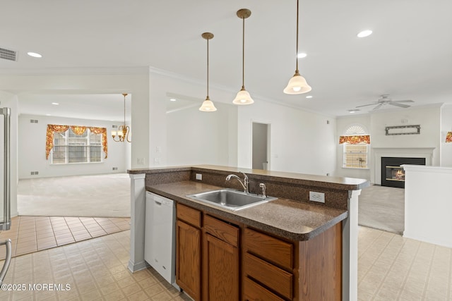 kitchen featuring white dishwasher, a sink, open floor plan, a glass covered fireplace, and decorative light fixtures