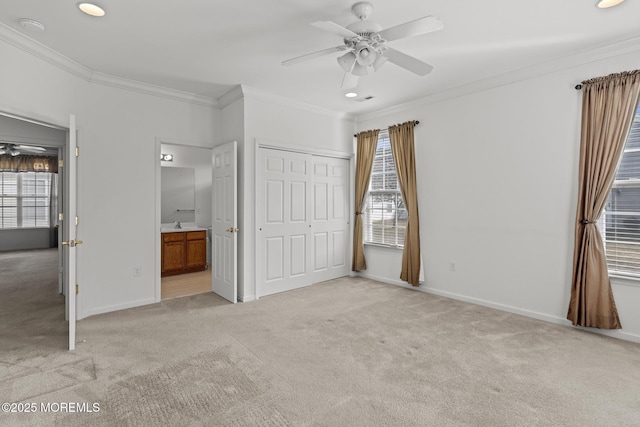 unfurnished bedroom with baseboards, light colored carpet, ensuite bath, ornamental molding, and a closet