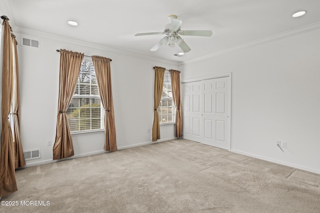 spare room featuring light carpet, visible vents, and crown molding