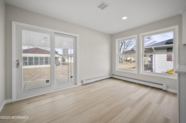 spare room with a baseboard radiator, visible vents, light wood-style flooring, and baseboards