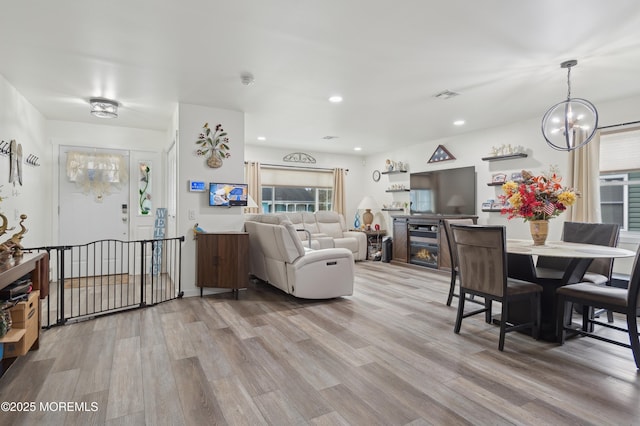 living area featuring a glass covered fireplace, visible vents, light wood-style flooring, and recessed lighting