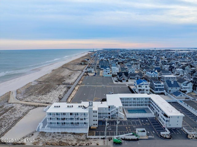 aerial view at dusk with a water view and a beach view