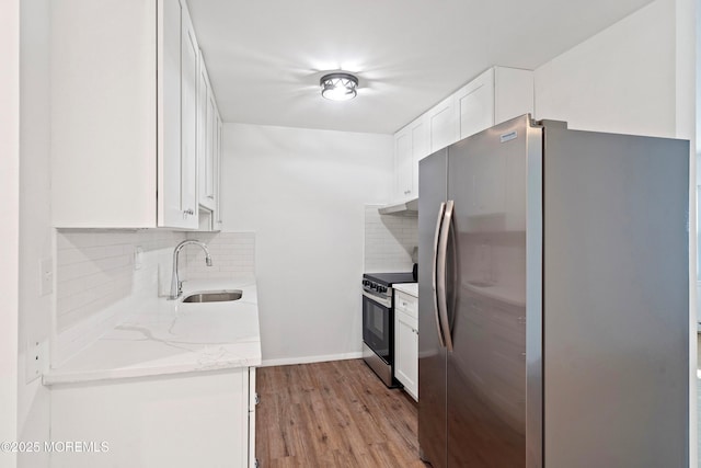 kitchen with white cabinetry, light stone countertops, light hardwood / wood-style floors, sink, and appliances with stainless steel finishes