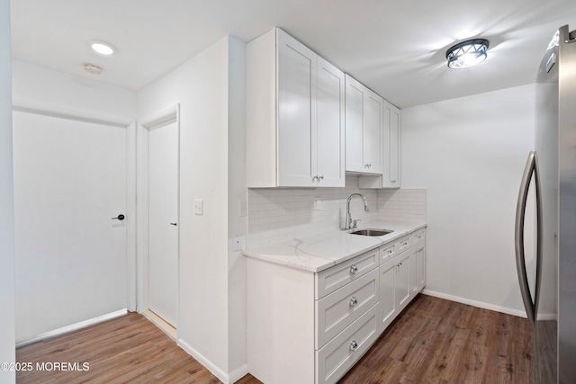 kitchen featuring hardwood / wood-style flooring, tasteful backsplash, stainless steel fridge, sink, and white cabinetry