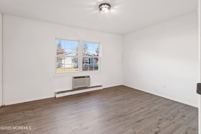 empty room featuring an AC wall unit, dark wood-type flooring, and baseboard heating