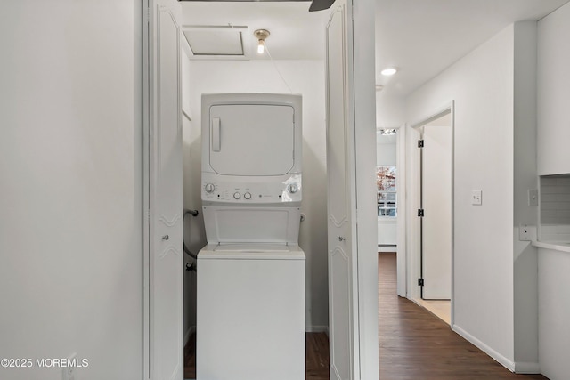 clothes washing area featuring dark wood-type flooring and stacked washer and clothes dryer