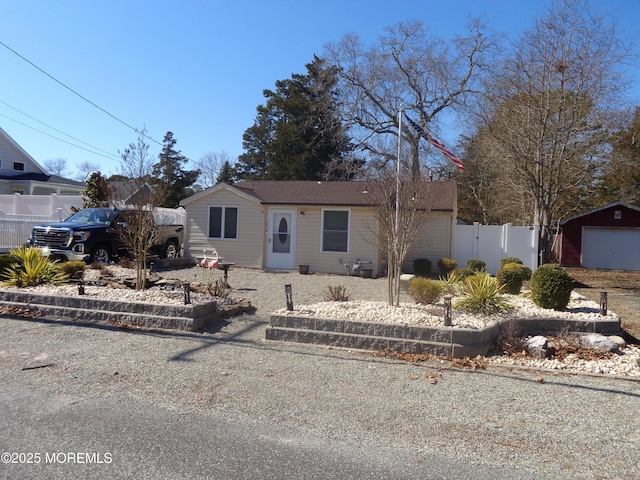 view of front of house featuring a garage, an outbuilding, and fence