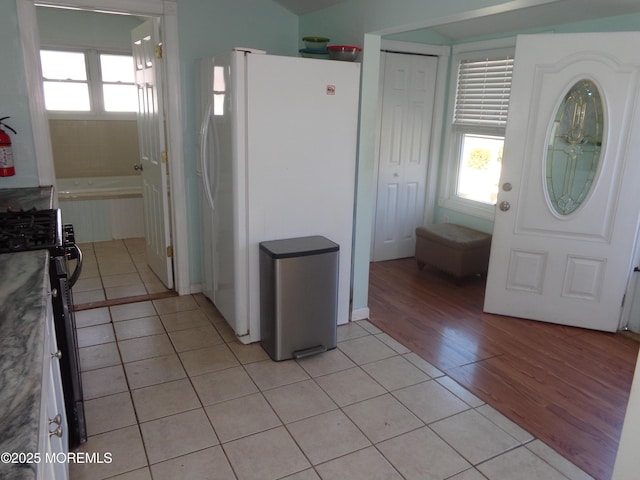 kitchen with a wealth of natural light, light tile patterned flooring, gas range oven, and freestanding refrigerator