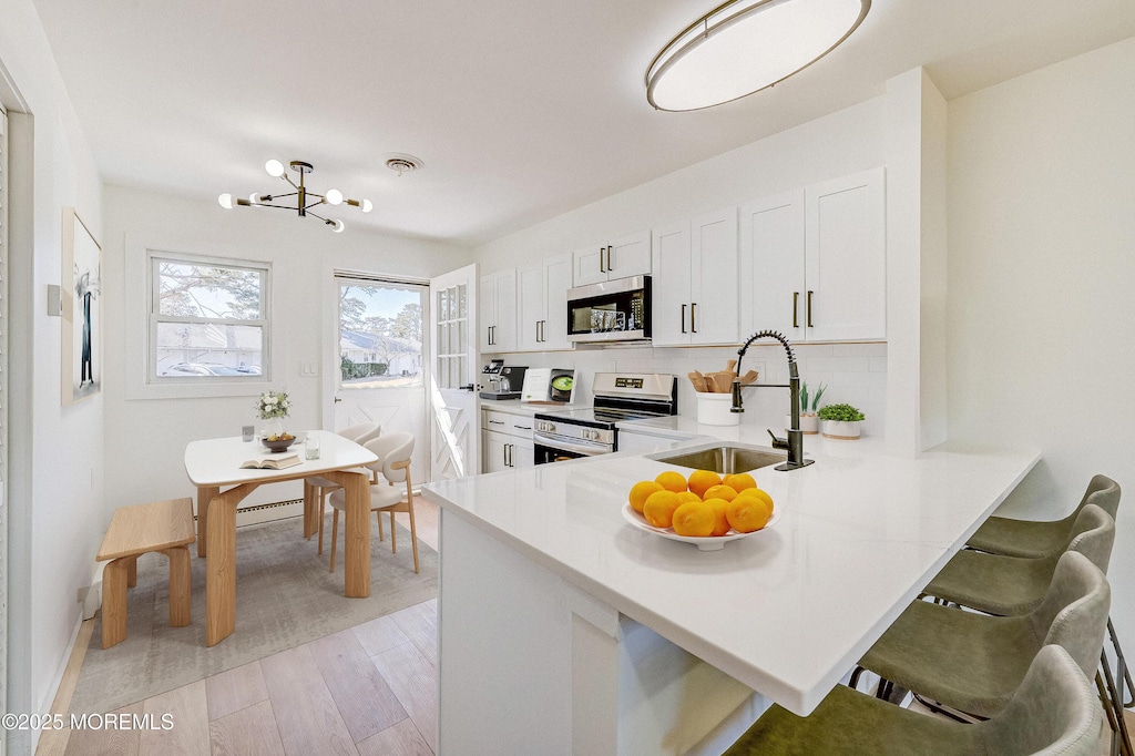 5A Sterling St, Manchester, NJ 08759 - kitchen with stainless steel appliances, a peninsula, a sink, white cabinets, and light countertops