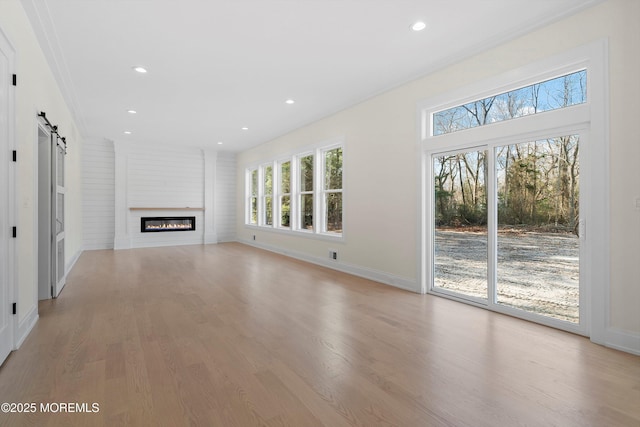 unfurnished living room featuring light hardwood / wood-style floors and a barn door