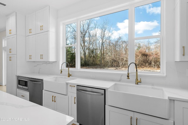 kitchen featuring white cabinetry, stainless steel appliances, light stone counters, and sink