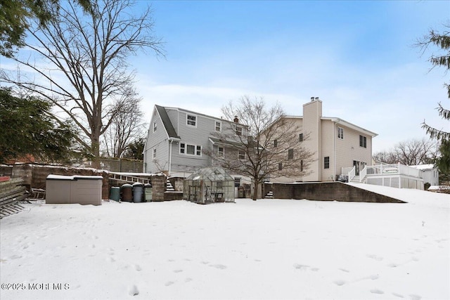 snow covered back of property featuring a jacuzzi and an outbuilding