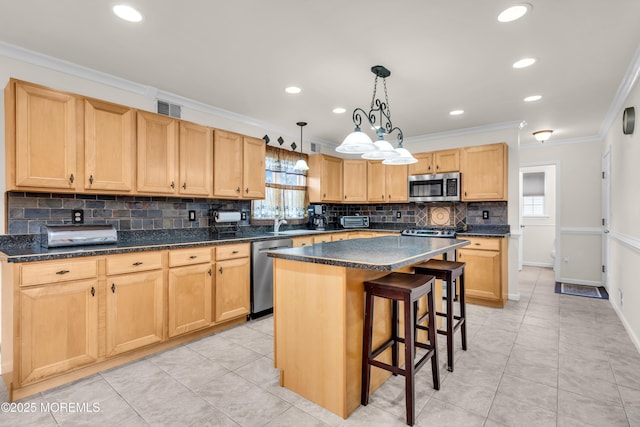 kitchen with a center island, ornamental molding, light brown cabinetry, appliances with stainless steel finishes, and a kitchen breakfast bar