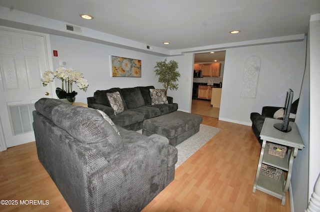 living area with visible vents, light wood-style floors, and recessed lighting