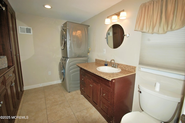 bathroom with stacked washing maching and dryer, vanity, visible vents, tile patterned flooring, and toilet