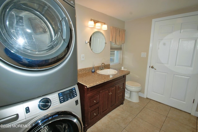 bathroom with vanity, stacked washer / dryer, toilet, and tile patterned floors