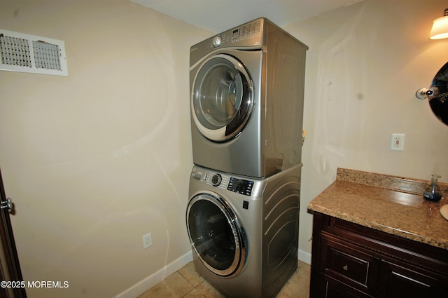 laundry room with stacked washer / drying machine, visible vents, light tile patterned floors, and baseboards