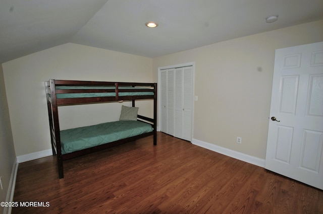 unfurnished bedroom with dark wood-style flooring, baseboards, a closet, and vaulted ceiling