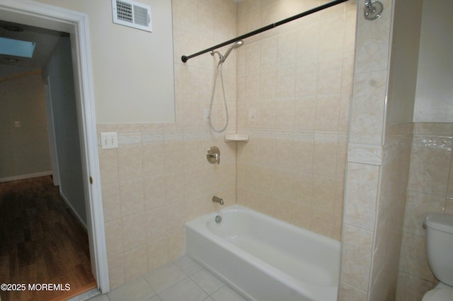 full bath with tile walls, visible vents, shower / bathtub combination, toilet, and tile patterned floors