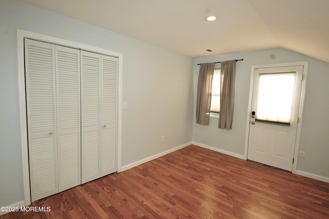 unfurnished bedroom featuring wood finished floors, baseboards, recessed lighting, vaulted ceiling, and a closet