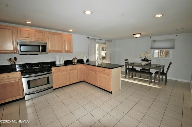 kitchen featuring decorative backsplash, light tile patterned floors, recessed lighting, stainless steel appliances, and a peninsula