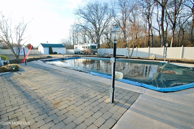 view of pool with a patio, fence, an outbuilding, and a fenced in pool