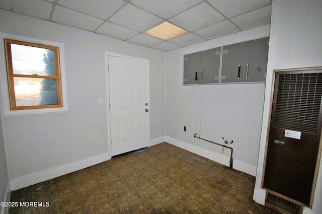 spare room featuring baseboards, a heating unit, and a drop ceiling