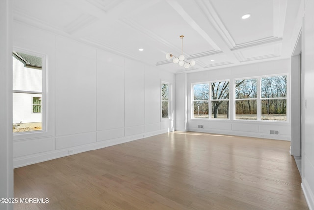 unfurnished room with beam ceiling, an inviting chandelier, wood-type flooring, and coffered ceiling