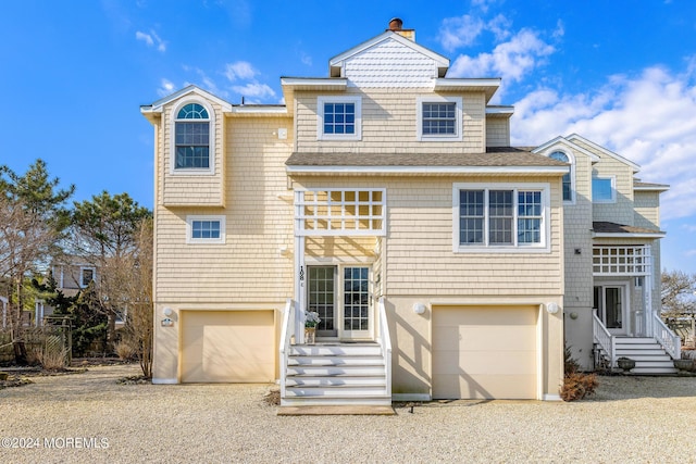 shingle-style home with a garage, driveway, and a chimney