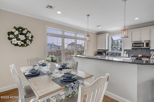 dining space featuring hardwood / wood-style floors and crown molding