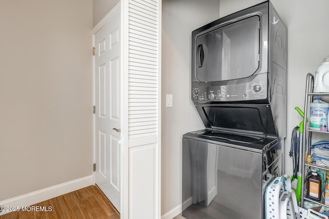 laundry room with hardwood / wood-style flooring and stacked washing maching and dryer