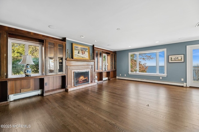 unfurnished living room featuring a healthy amount of sunlight, baseboard heating, and wood finished floors