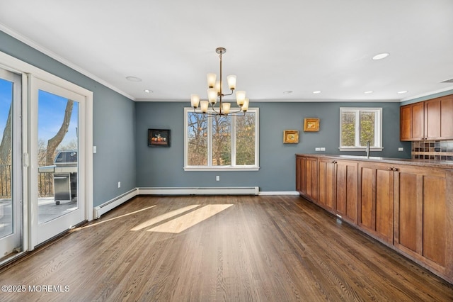 unfurnished dining area with dark wood-style floors, crown molding, a sink, and baseboards