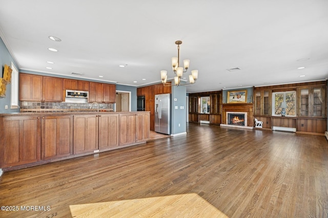 kitchen featuring ornamental molding, open floor plan, wood finished floors, baseboard heating, and stainless steel appliances