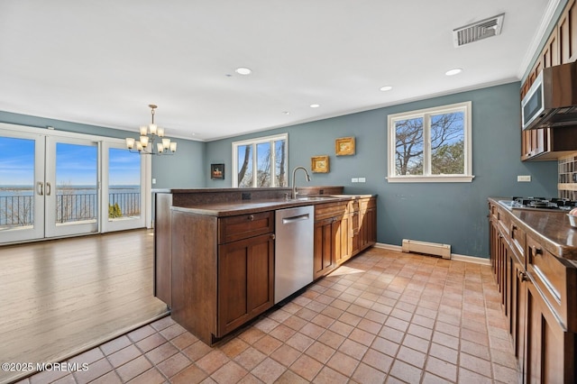 kitchen featuring stainless steel appliances, dark countertops, visible vents, a healthy amount of sunlight, and a sink