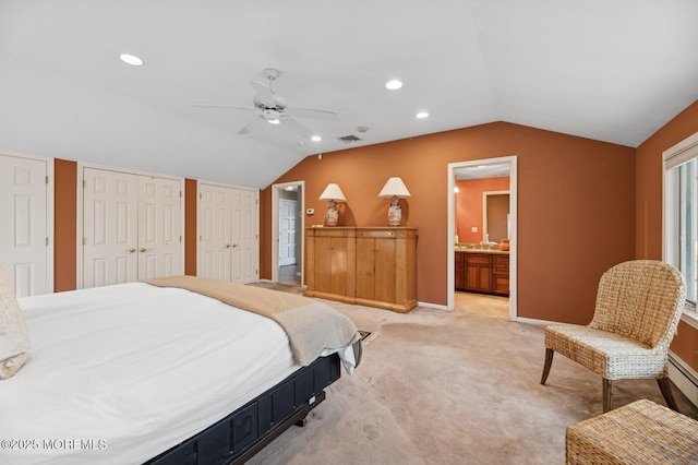 bedroom featuring multiple closets, lofted ceiling, light carpet, ensuite bath, and baseboards