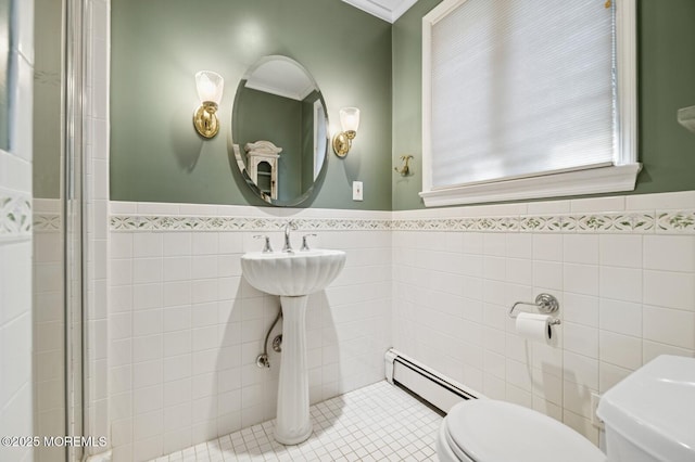 bathroom featuring toilet, a baseboard radiator, tile walls, and wainscoting