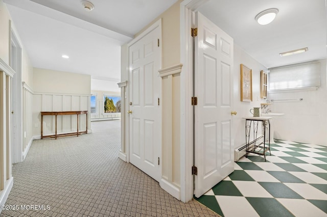 corridor featuring a baseboard heating unit, carpet floors, and tile patterned floors