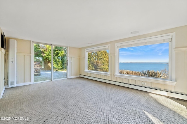 interior space with a baseboard heating unit, a water view, and a decorative wall