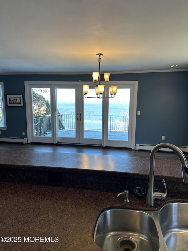 interior space with a baseboard heating unit, a healthy amount of sunlight, a sink, and crown molding