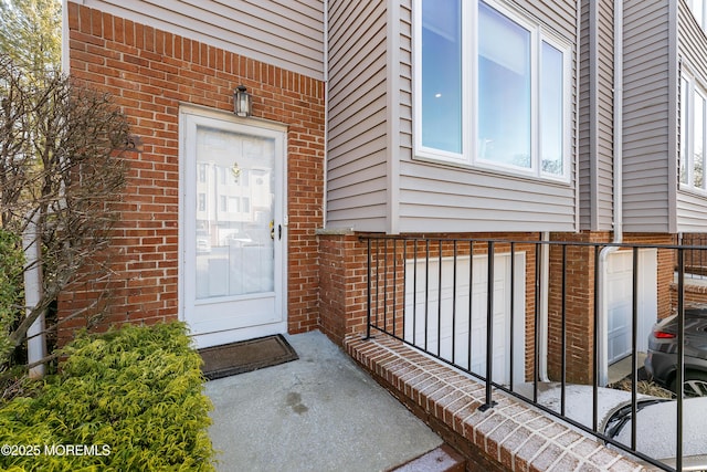 doorway to property with brick siding and an attached garage