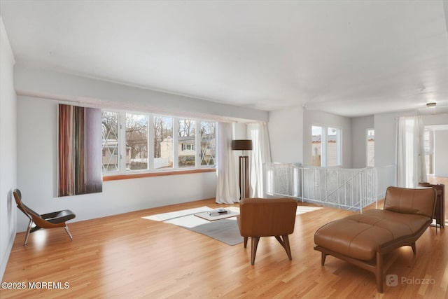 living area with a wealth of natural light, light wood-style flooring, and an upstairs landing