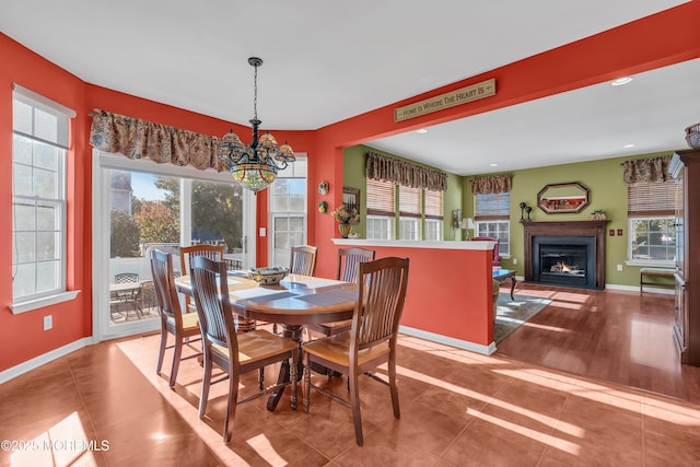 dining room with a notable chandelier, a fireplace with flush hearth, a healthy amount of sunlight, and baseboards