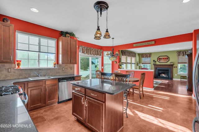 kitchen featuring dishwasher, decorative light fixtures, a center island, a sink, and a breakfast bar area